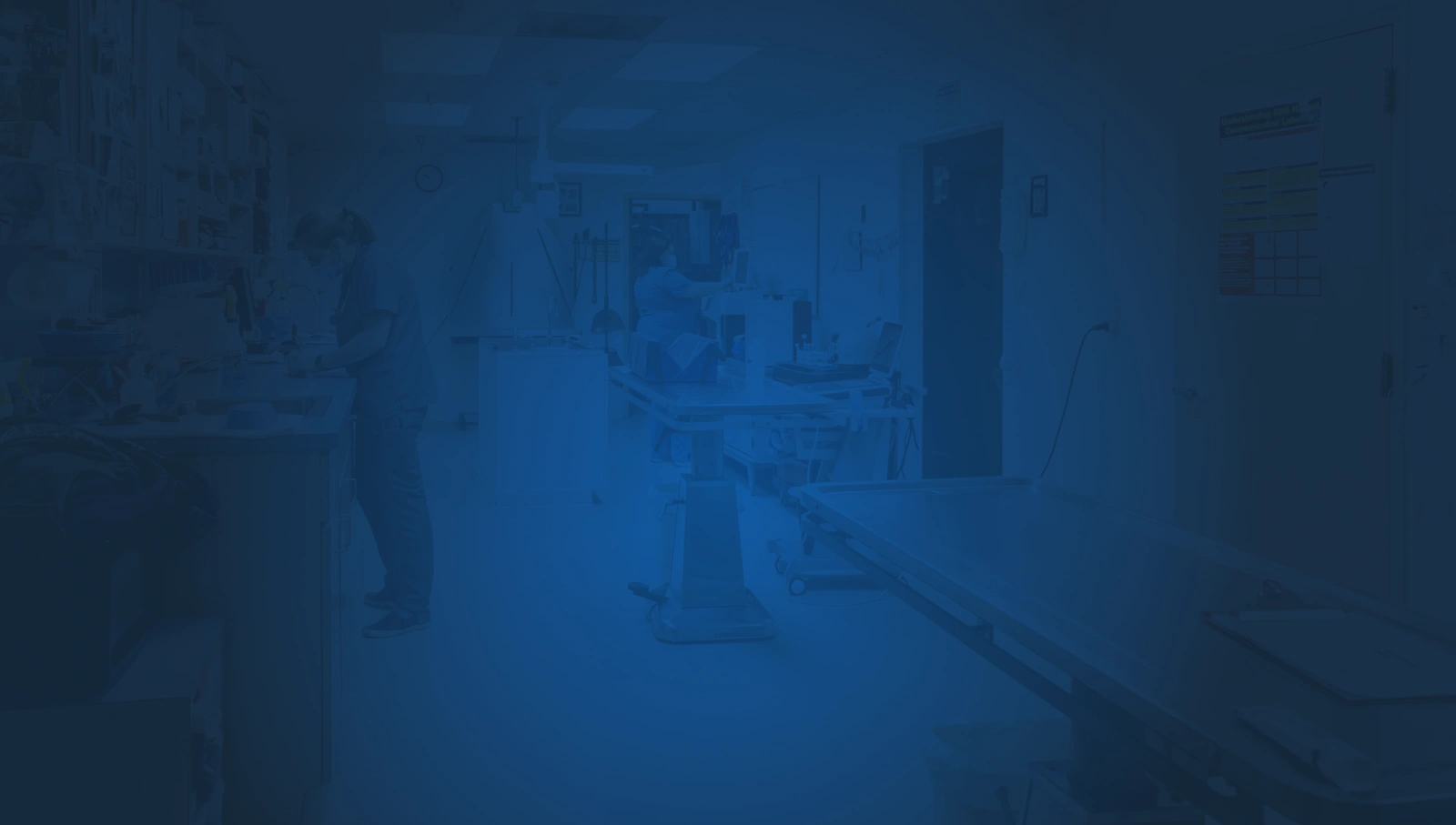 A hospital room featuring a blue background, equipped with a bed, medical equipment, and a window for natural light.